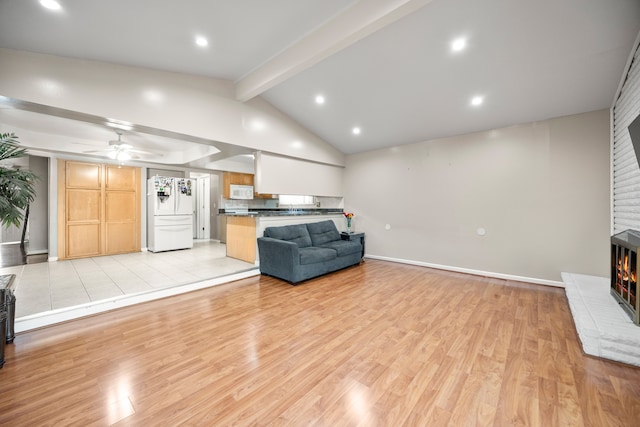 living room featuring lofted ceiling with beams, ceiling fan, a fireplace, and light hardwood / wood-style floors