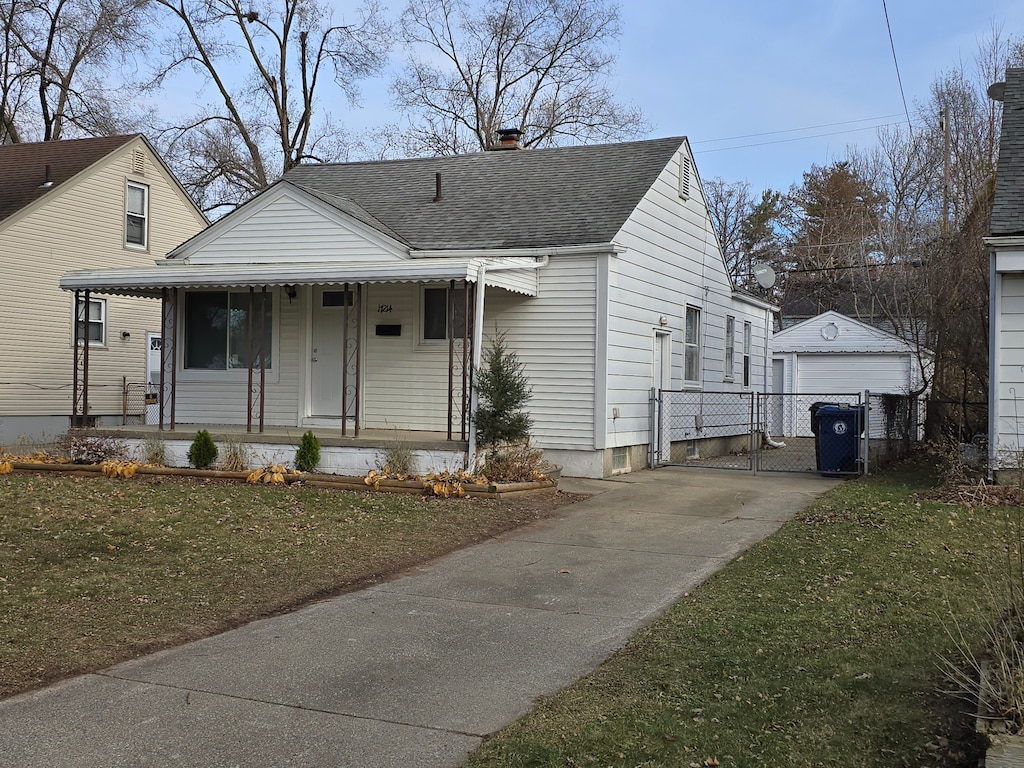 bungalow with a porch, a garage, an outdoor structure, and a front yard