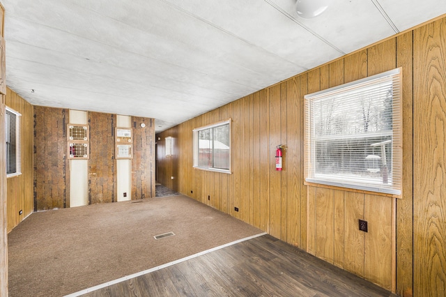 empty room with dark wood-type flooring and wooden walls