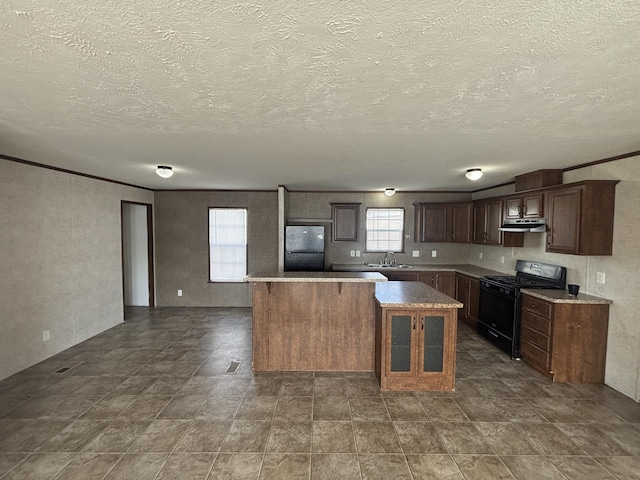 kitchen with sink, dark brown cabinets, a center island, black appliances, and a textured ceiling