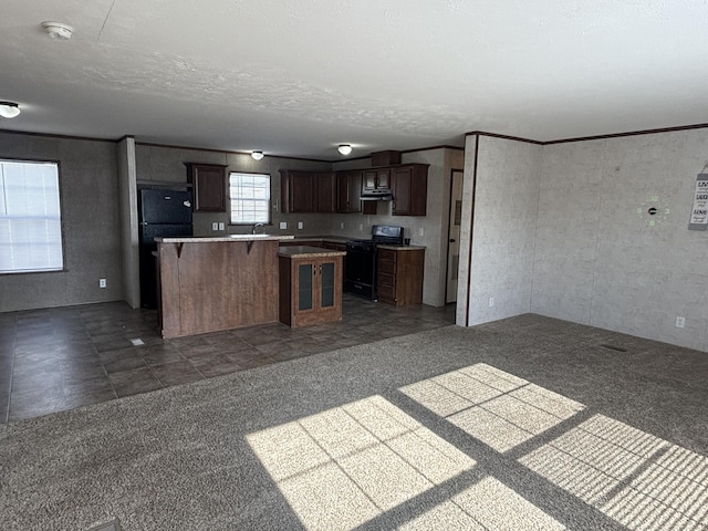 kitchen with dark colored carpet, a center island, dark brown cabinets, and black appliances