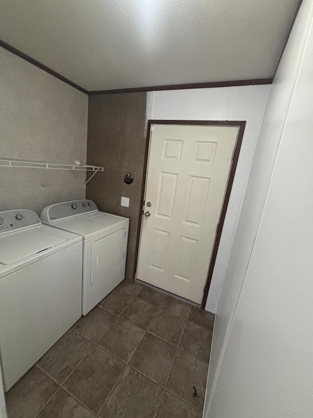 laundry area with ornamental molding, washer and clothes dryer, and dark tile patterned floors