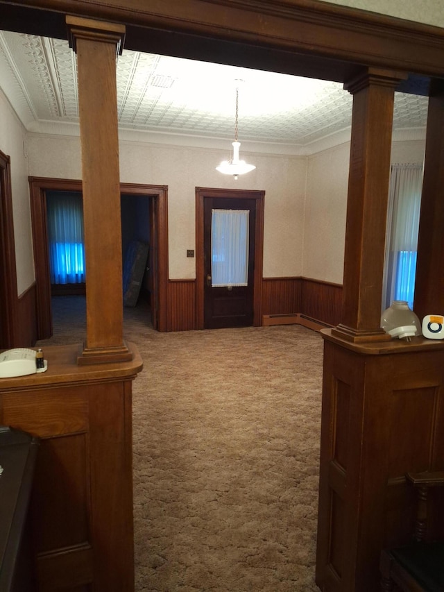 corridor with crown molding, a baseboard radiator, decorative columns, and carpet flooring