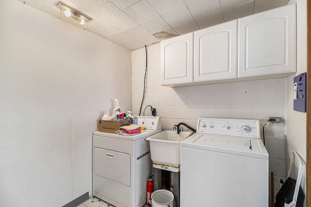 laundry room with sink, washing machine and dryer, and cabinets