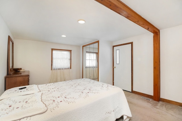 bedroom with beam ceiling and light colored carpet