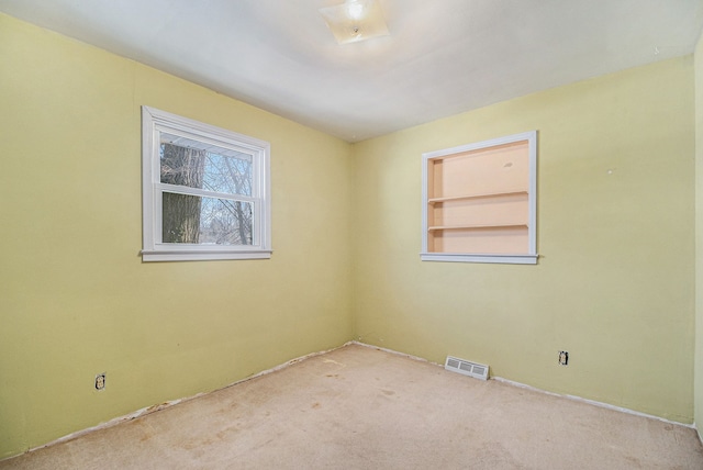 carpeted spare room featuring built in features