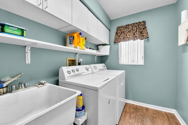 laundry room with hardwood / wood-style flooring, cabinets, sink, and washing machine and dryer