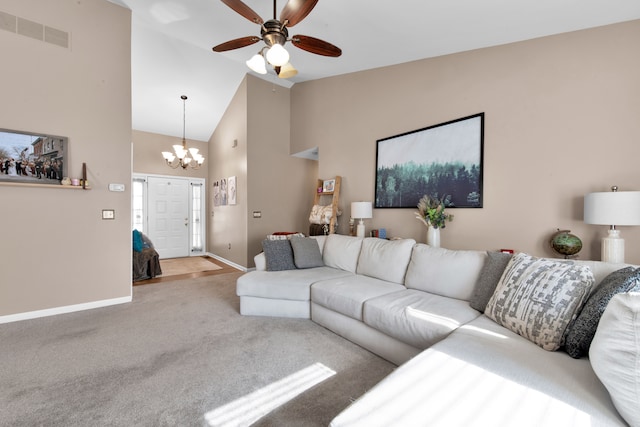 carpeted living room featuring ceiling fan with notable chandelier and high vaulted ceiling