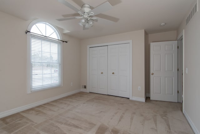 unfurnished bedroom with light colored carpet, a closet, and ceiling fan