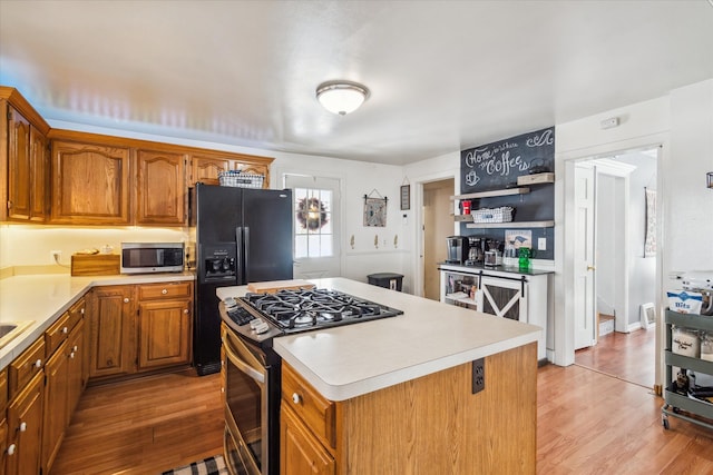 kitchen with light wood-type flooring, stainless steel appliances, and a kitchen island