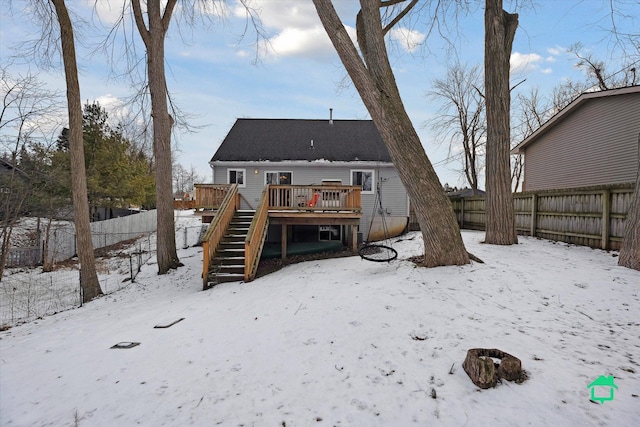 snow covered rear of property with a wooden deck