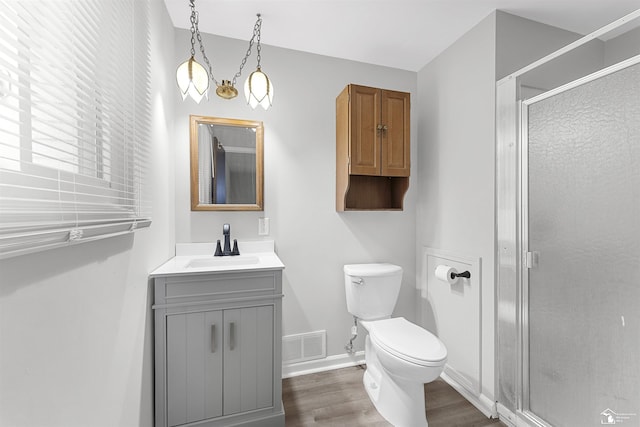 bathroom with vanity, hardwood / wood-style flooring, a shower with door, and toilet