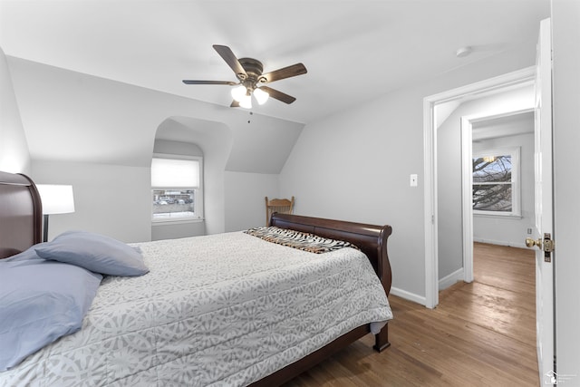 bedroom featuring hardwood / wood-style flooring, ceiling fan, vaulted ceiling, and multiple windows