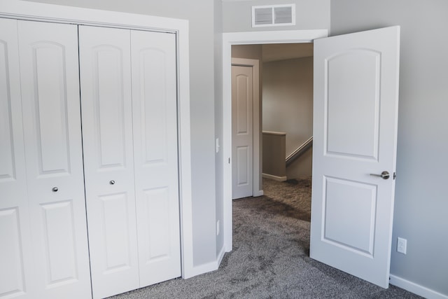 unfurnished bedroom featuring dark carpet and a closet