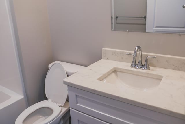 bathroom with vanity, a bath, and toilet