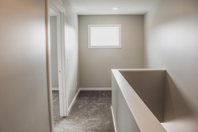 hall with dark colored carpet