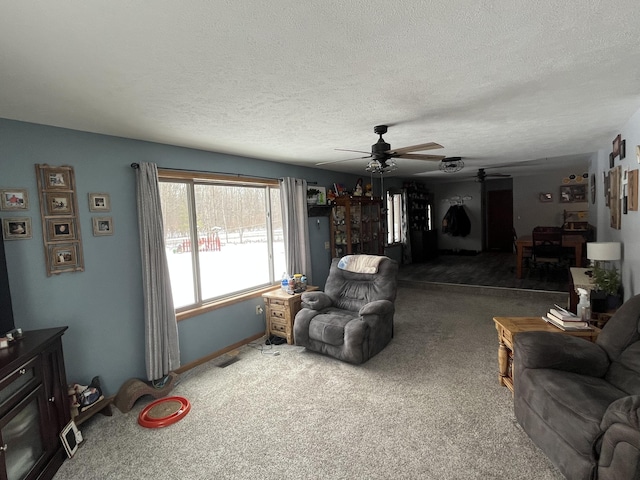 living room featuring ceiling fan, a textured ceiling, and carpet