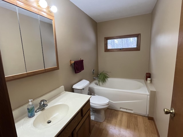 bathroom featuring vanity, wood-type flooring, toilet, and a bathing tub