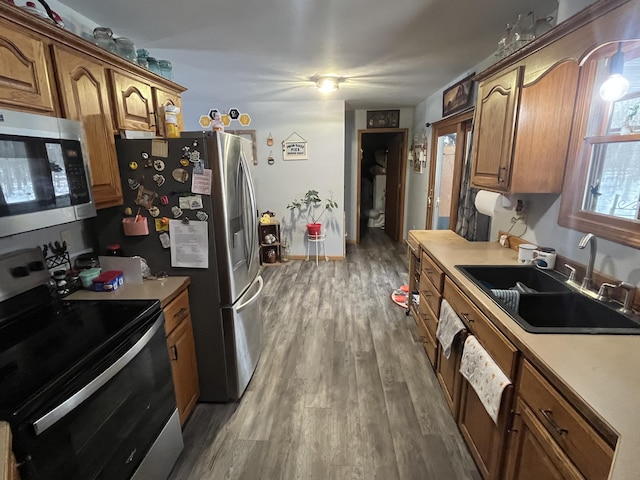 kitchen featuring stainless steel appliances, wood-type flooring, and sink