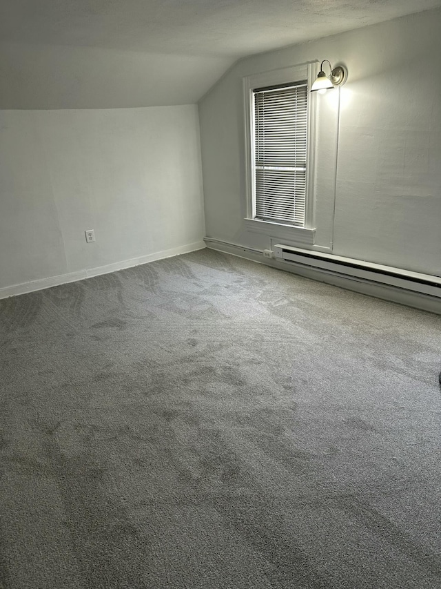 additional living space with a baseboard heating unit, vaulted ceiling, and carpet