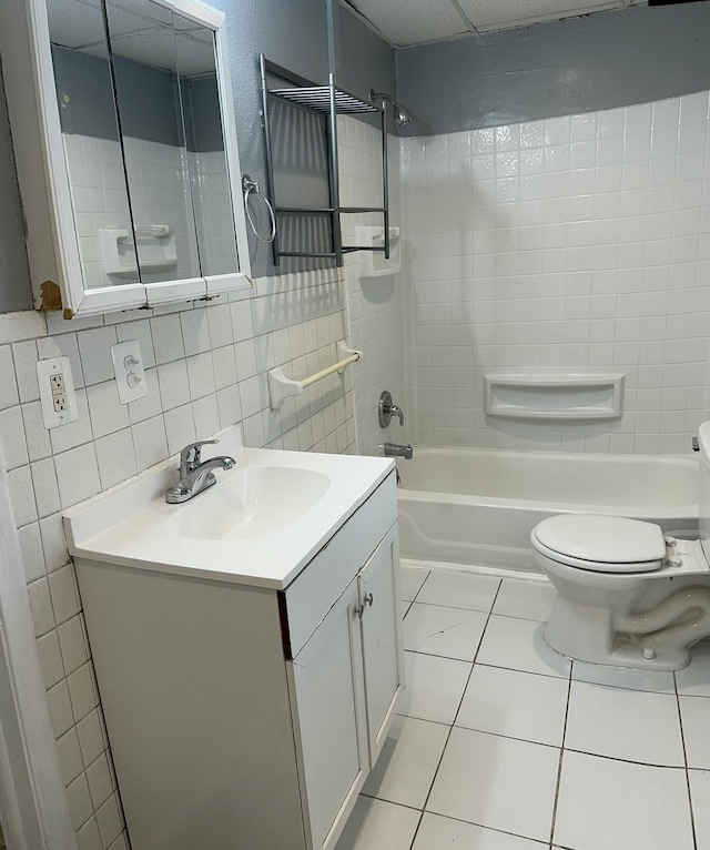 full bathroom with tile walls, tiled shower / bath combo, vanity, tile patterned flooring, and toilet