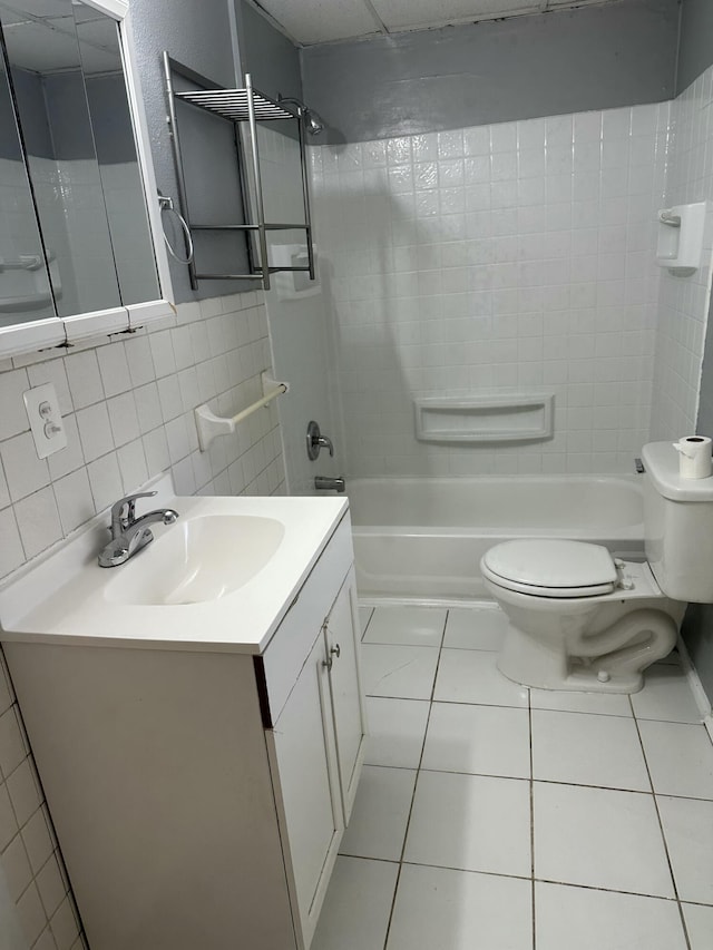 full bathroom featuring tile patterned flooring, tile walls, vanity, toilet, and tiled shower / bath