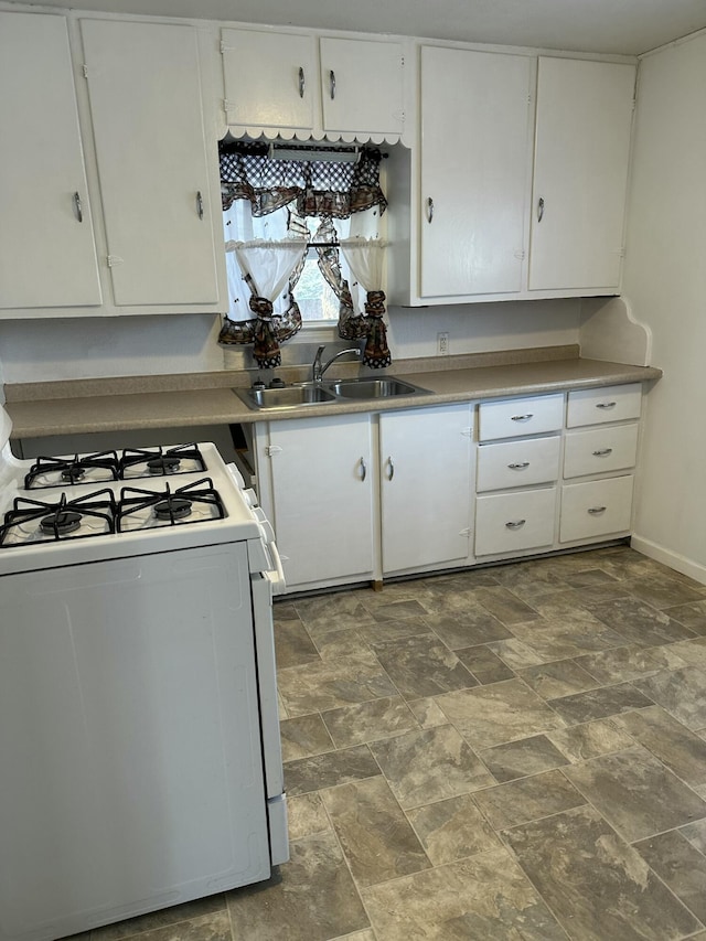 kitchen featuring sink, white gas stove, and white cabinets