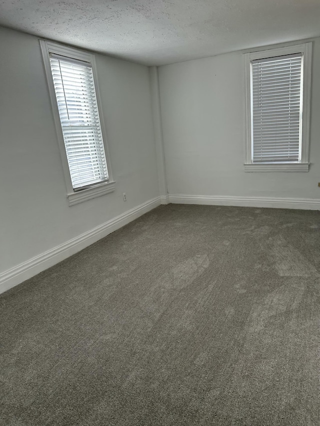 empty room with a textured ceiling and dark colored carpet