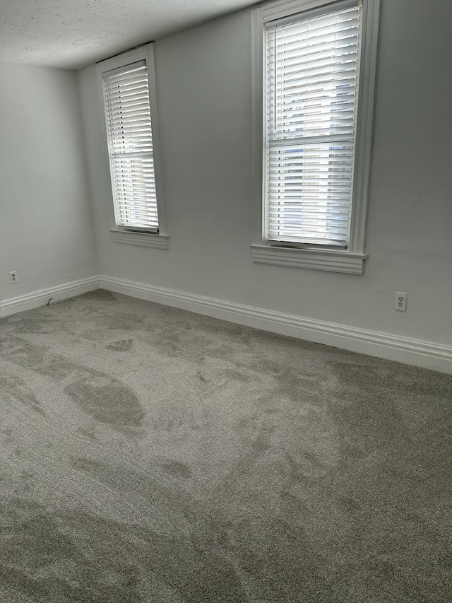 carpeted spare room with a textured ceiling