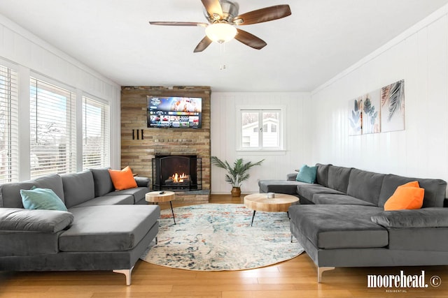 living room with a brick fireplace, wood-type flooring, and ceiling fan