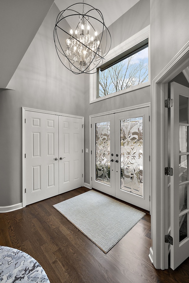 entrance foyer featuring french doors, dark hardwood / wood-style floors, an inviting chandelier, and a high ceiling