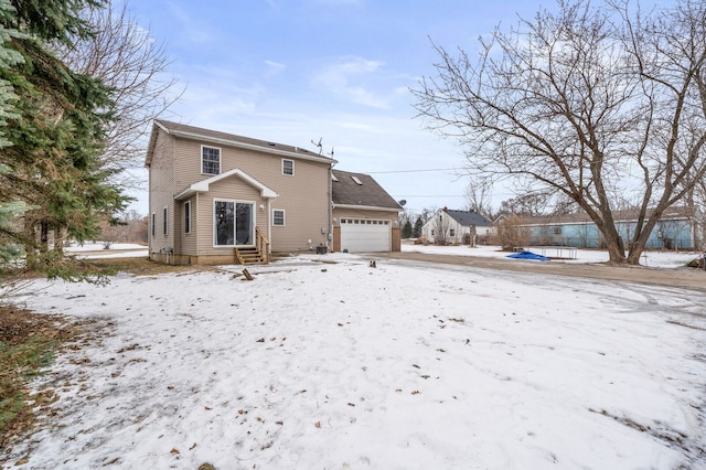 snow covered rear of property with a garage