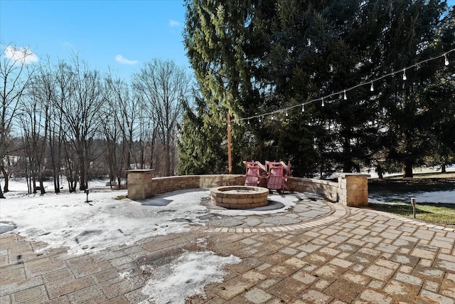 snow covered patio with a fire pit