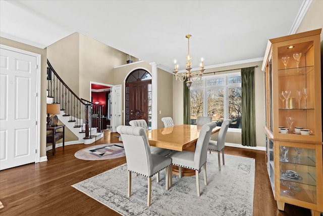 dining space with dark wood-type flooring, ornamental molding, and a chandelier