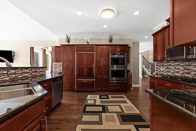 kitchen with sink, crown molding, stainless steel appliances, dark hardwood / wood-style floors, and dark stone counters