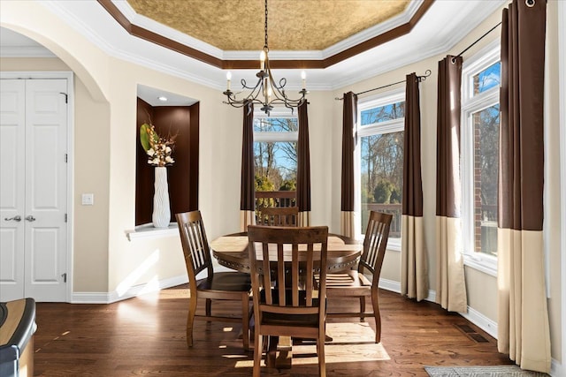 dining room featuring dark hardwood / wood-style flooring, ornamental molding, a raised ceiling, and a chandelier