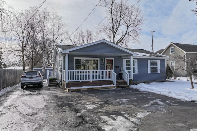 bungalow-style house featuring a shingled roof, fence, and a porch