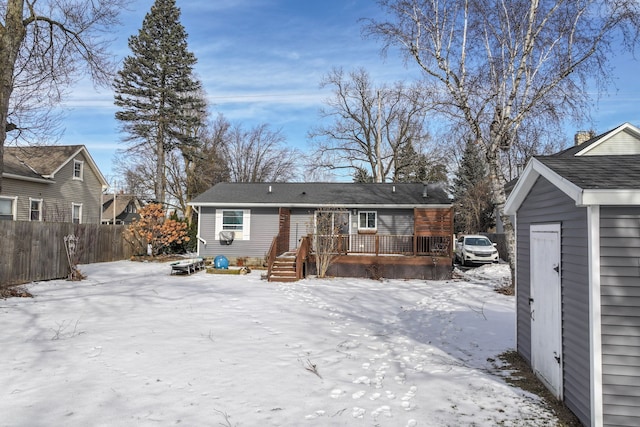 snow covered house with a deck and fence