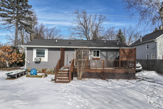 snow covered rear of property featuring fence and a wooden deck