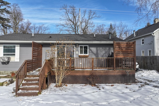 snow covered property with a deck and fence