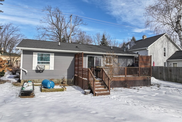 snow covered house featuring fence and a deck