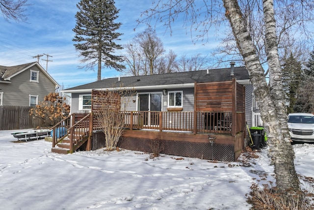 snow covered back of property with fence and a deck