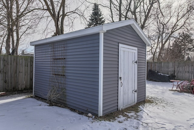 snow covered structure with a storage unit, an outdoor structure, and fence