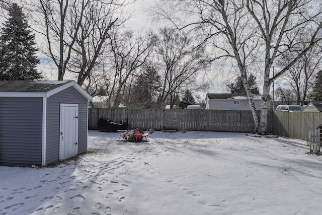 yard covered in snow featuring an outbuilding, a storage shed, and a fenced backyard