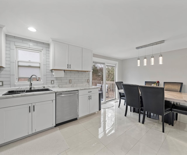 kitchen with tasteful backsplash, sink, white cabinets, hanging light fixtures, and stainless steel dishwasher