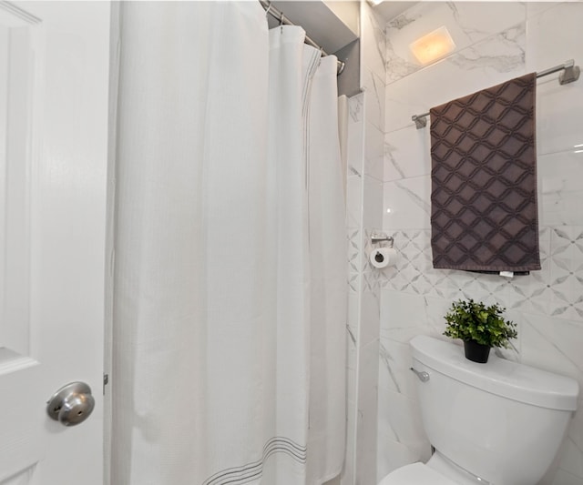 bathroom featuring tile walls, curtained shower, and toilet