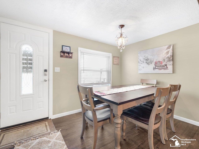 dining room featuring dark wood-type flooring, a textured ceiling, and a notable chandelier