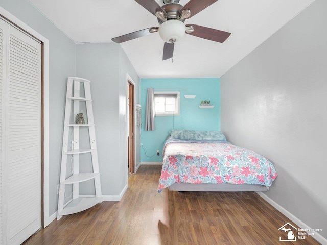 bedroom featuring dark wood-type flooring, ceiling fan, and a closet