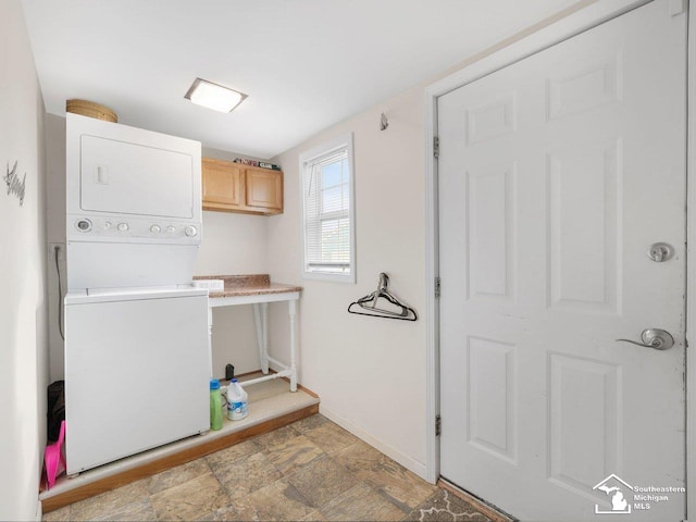 laundry area with stacked washer / dryer and cabinets