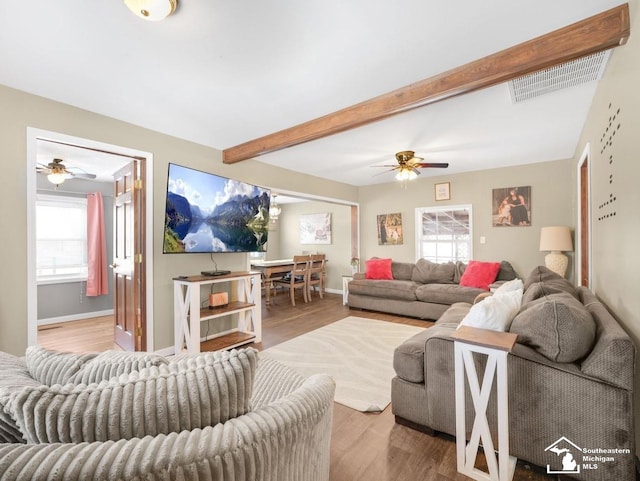 living room featuring beam ceiling, plenty of natural light, and wood-type flooring